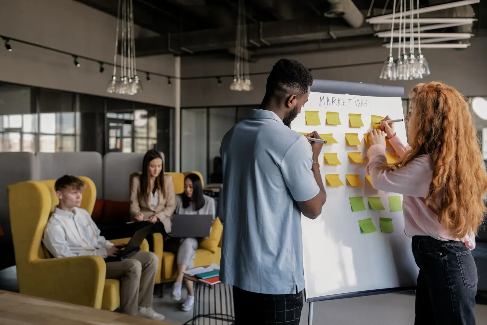 Dos personas organizando ideas en una pizarra de trabajo.