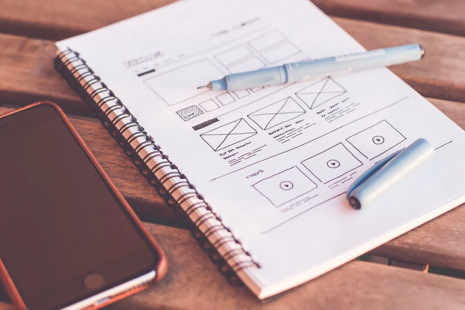 Bocetos de interfaces en un cuaderno junto a un teléfono.