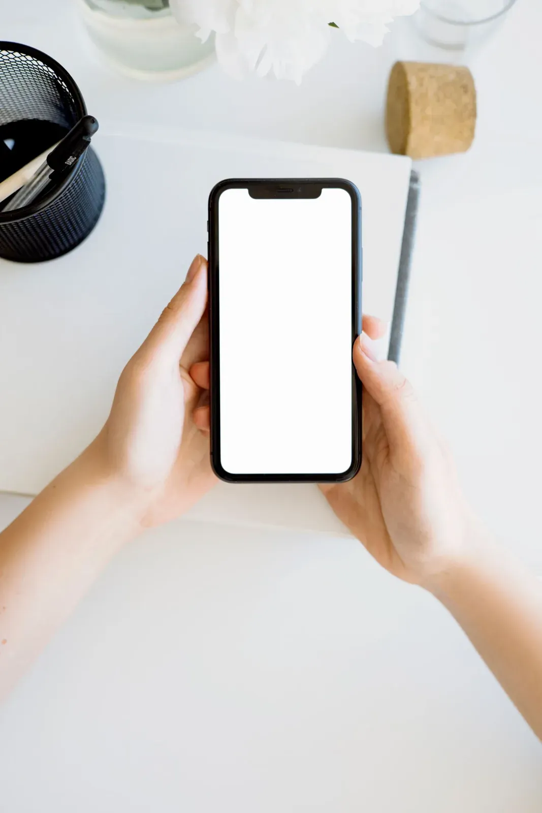 Manos sosteniendo un teléfono con la pantalla vacía.
