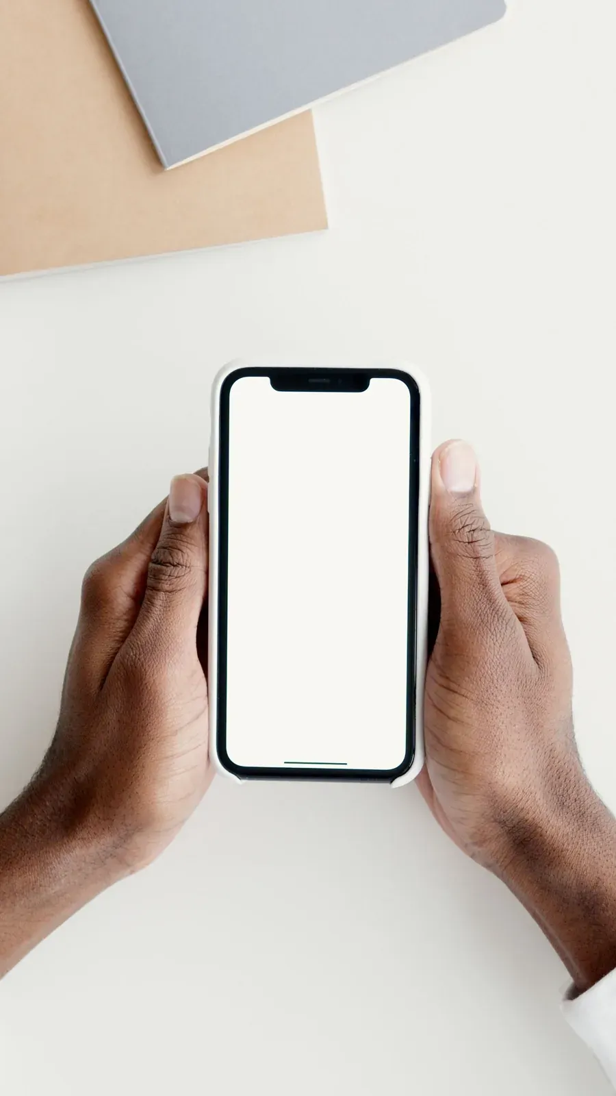 Persona sujetando un teléfono sobre una mesa de trabajo.