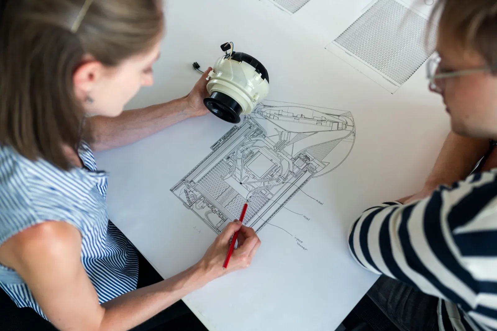 Dos profesionales examinando un diseño técnico.
