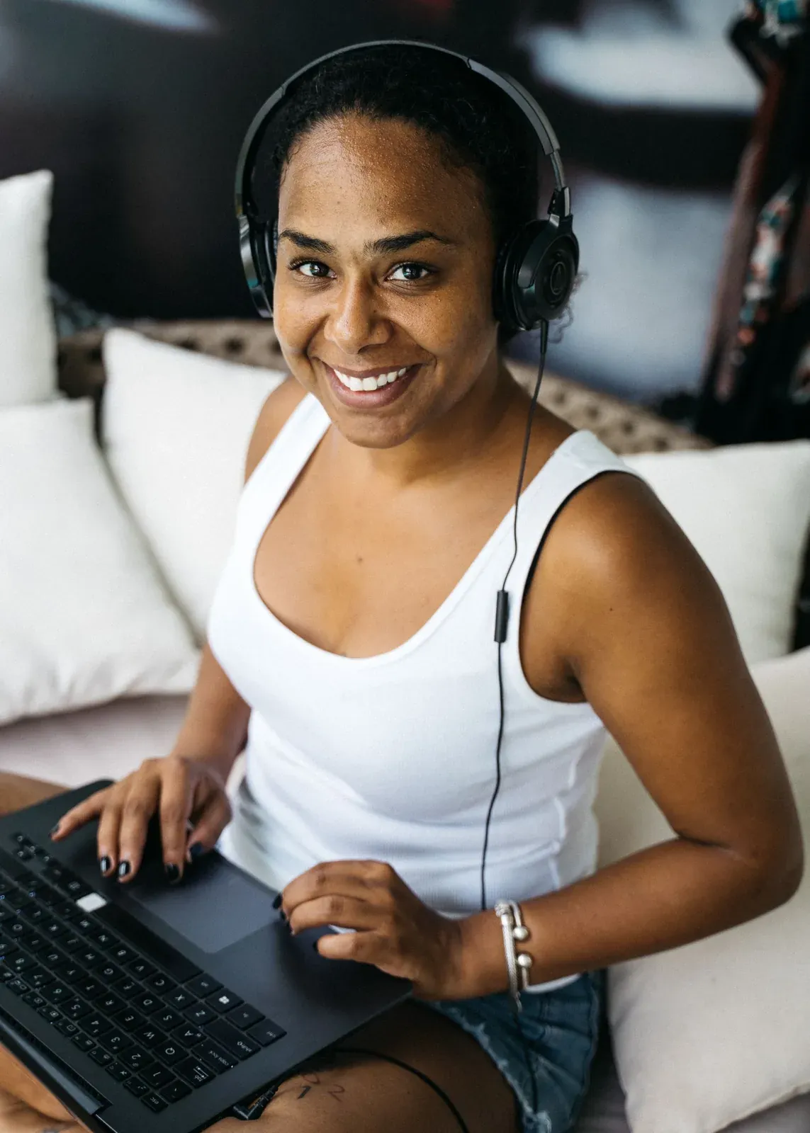 Mujer con auriculares consulta un portátil en una habitación.