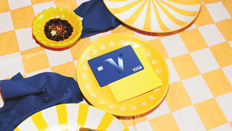 Tarjeta Visa con el nuevo símbolo V sobre una composición amarilla de la identidad visual actualizada